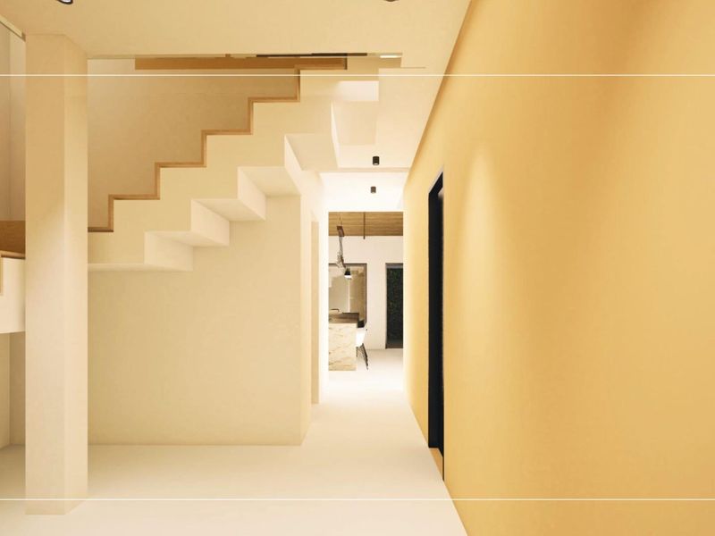 A bright, modern hallway featuring a clean staircase design and recessed lighting, leading towards an open-plan living area.
