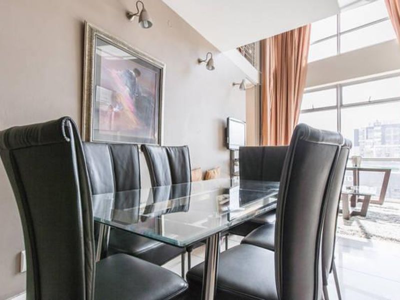 A bright, double-volume living area featuring large windows that provide ample natural light and a spacious, open atmosphere.