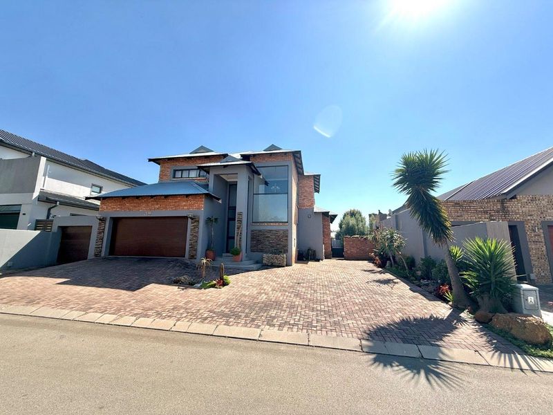 Modern double-story residential home featuring a brick and stone facade, large feature window, and a spacious paved driveway with an integrated double garage.