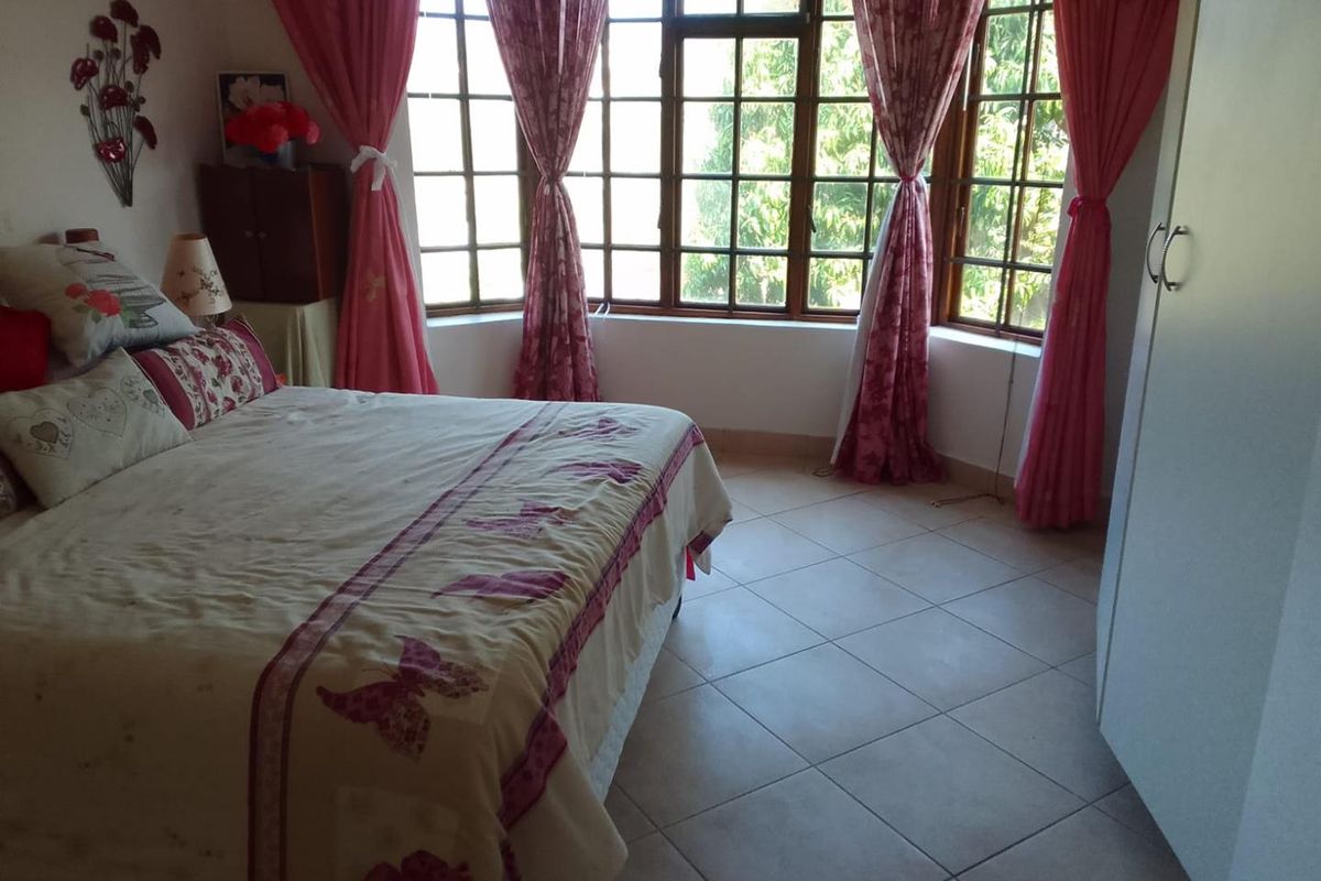 A bedroom featuring tiled flooring and large bay windows that provide natural light.