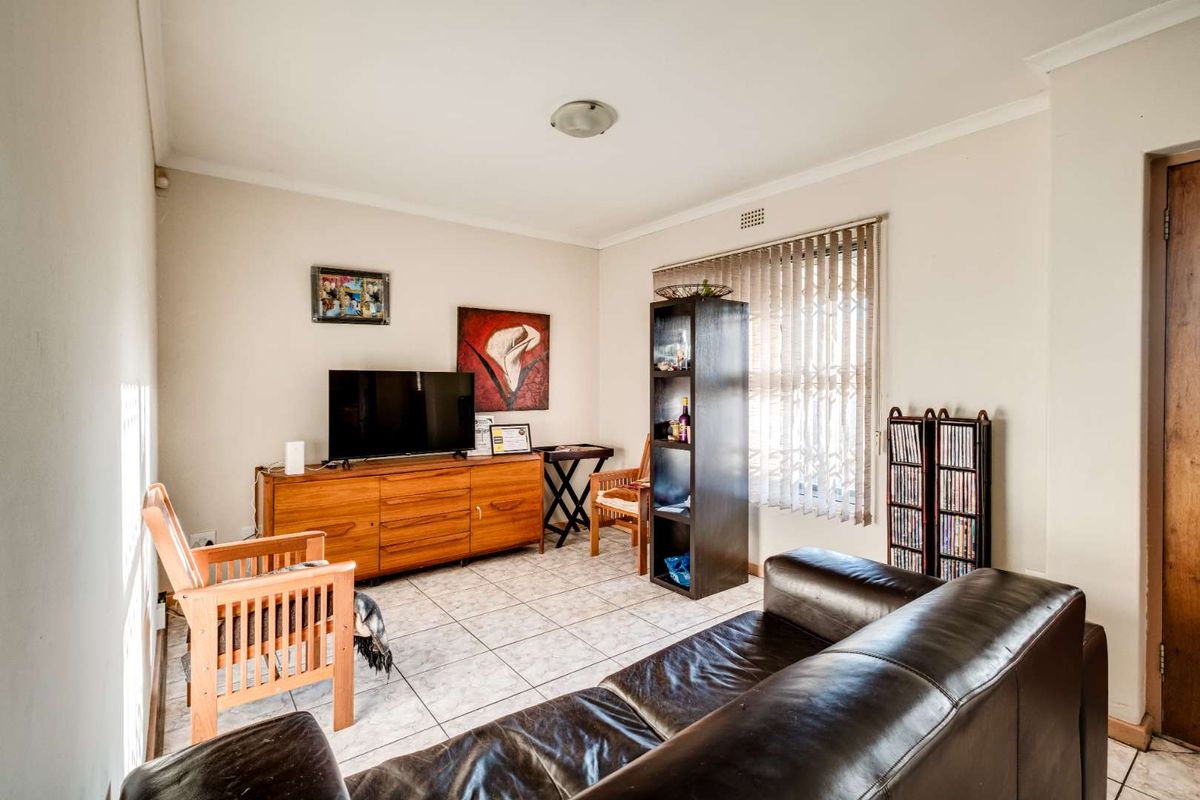 A living room featuring tiled flooring, vertical window blinds, and a ceiling-mounted light fixture.