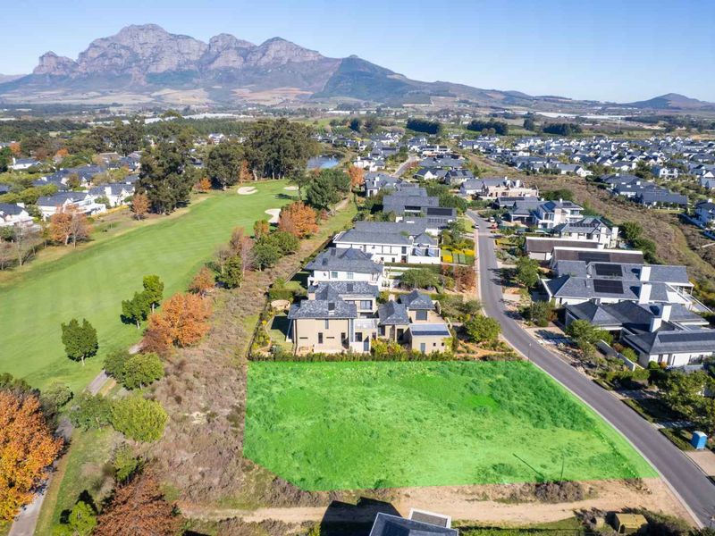 An aerial view of a vacant residential plot situated in a prime estate, featuring direct golf course frontage and convenient street access.