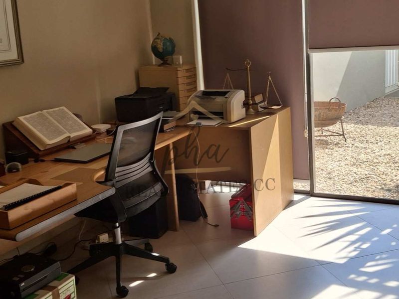 A functional home office featuring tiled flooring and a large sliding glass door providing direct access to an outdoor area.