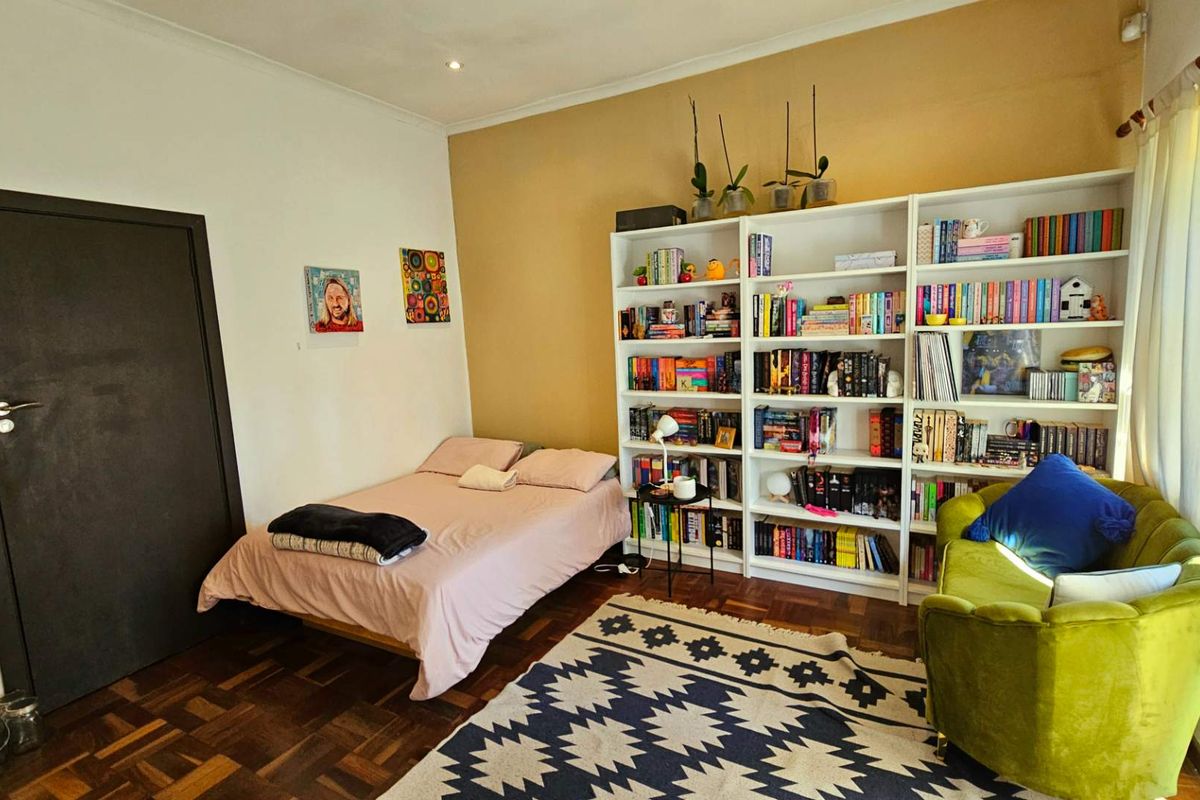 A bedroom featuring classic parquet flooring and a large built-in floor-to-ceiling shelving unit, providing ample storage space.