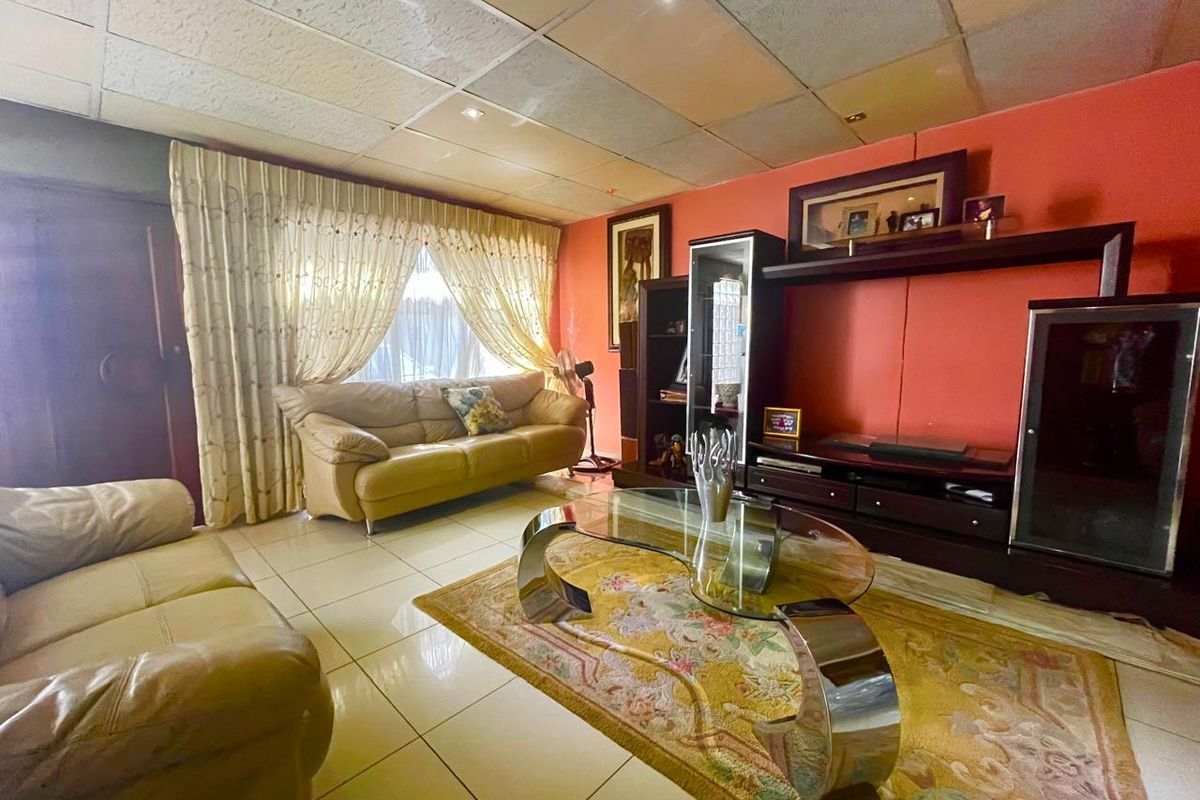 A living room featuring tiled flooring and a suspended ceiling with recessed lighting, offering a dated aesthetic ready for modernization.