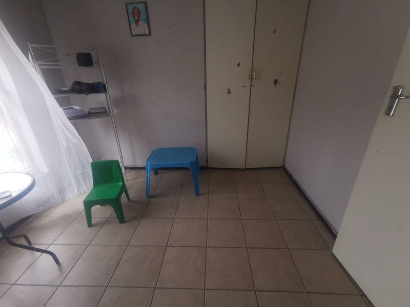 A bedroom featuring tiled flooring and a built-in cupboard, offering a functional space in need of cosmetic updates.