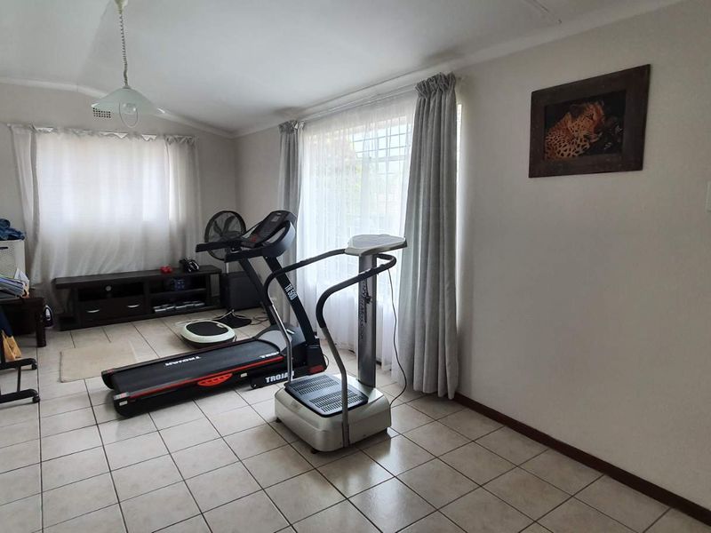 A functional room currently utilized as a home gym, featuring tiled flooring and neutral wall finishes, suitable for various multi-purpose uses.