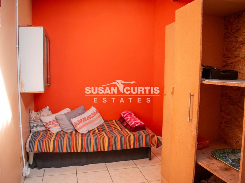 A compact bedroom featuring tiled flooring, a built-in cupboard, and a wall-mounted storage cabinet.