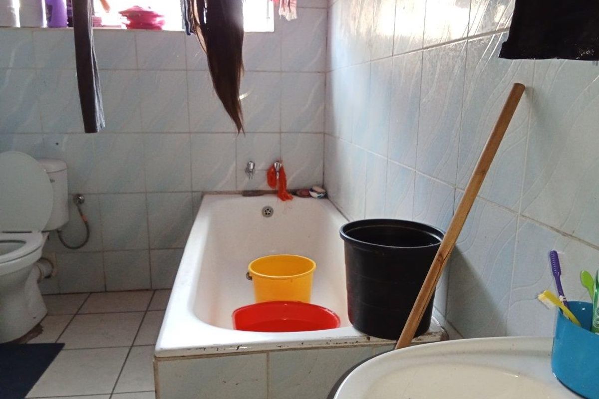 A functional bathroom featuring a standard bathtub, toilet, and tiled surfaces, currently requiring maintenance and cosmetic updates to improve its overall condition.