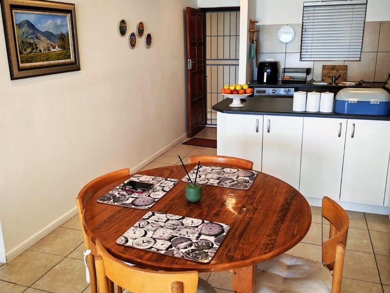 Open plan living and kitchen area featuring tiled flooring, white cabinetry with dark countertops, and direct access to a secure entrance.