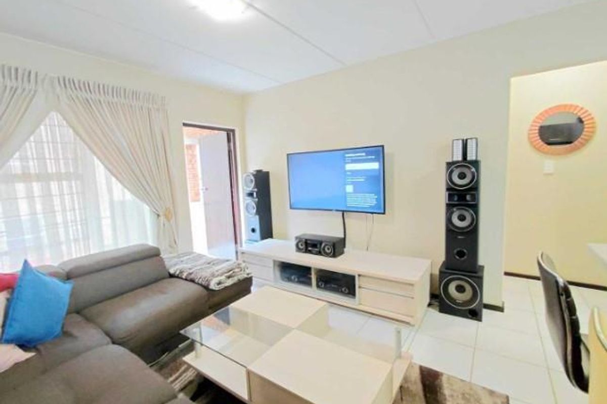 A comfortable living room featuring tiled flooring, neutral walls, and direct access to an outdoor balcony area.