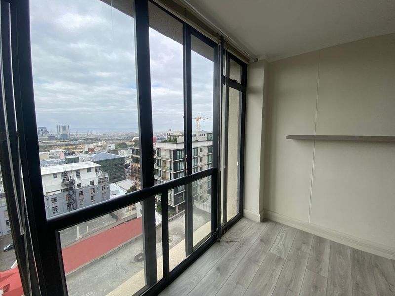 Bright living area featuring modern laminate flooring and large sliding glass doors that offer expansive city views.