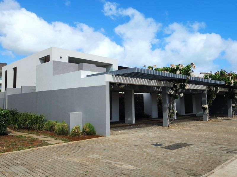 Modern townhouse exterior featuring a paved driveway, covered carport with pergola structure, and contemporary architectural design.
