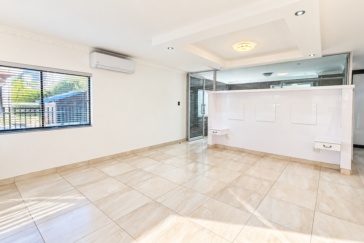 A bright, open-plan living area featuring neutral tiled flooring, recessed ceiling lighting, an air conditioning unit, and a modern built-in partition wall.