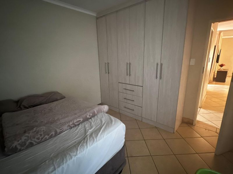 A bedroom featuring built-in cupboards with light wood-grain finish and tiled flooring, providing functional storage space.