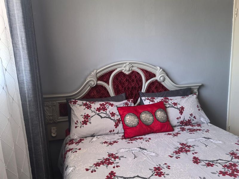 A bedroom featuring a decorative built-in headboard against a neutral grey wall.