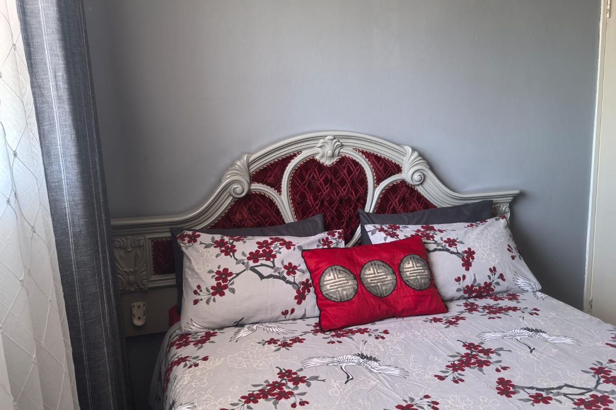 A bedroom featuring a decorative built-in headboard against a neutral grey wall.