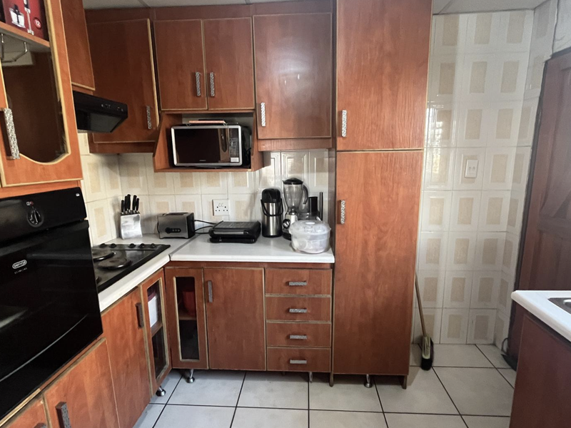 A functional kitchen featuring wood-tone cabinetry, built-in oven, gas hob, and tiled finishes, offering a classic layout with ample storage space.