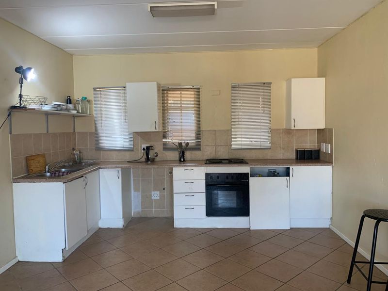A functional kitchen featuring built-in cabinetry, a tiled backsplash, a built-in oven with hob, and tiled flooring, offering potential for cosmetic updates.