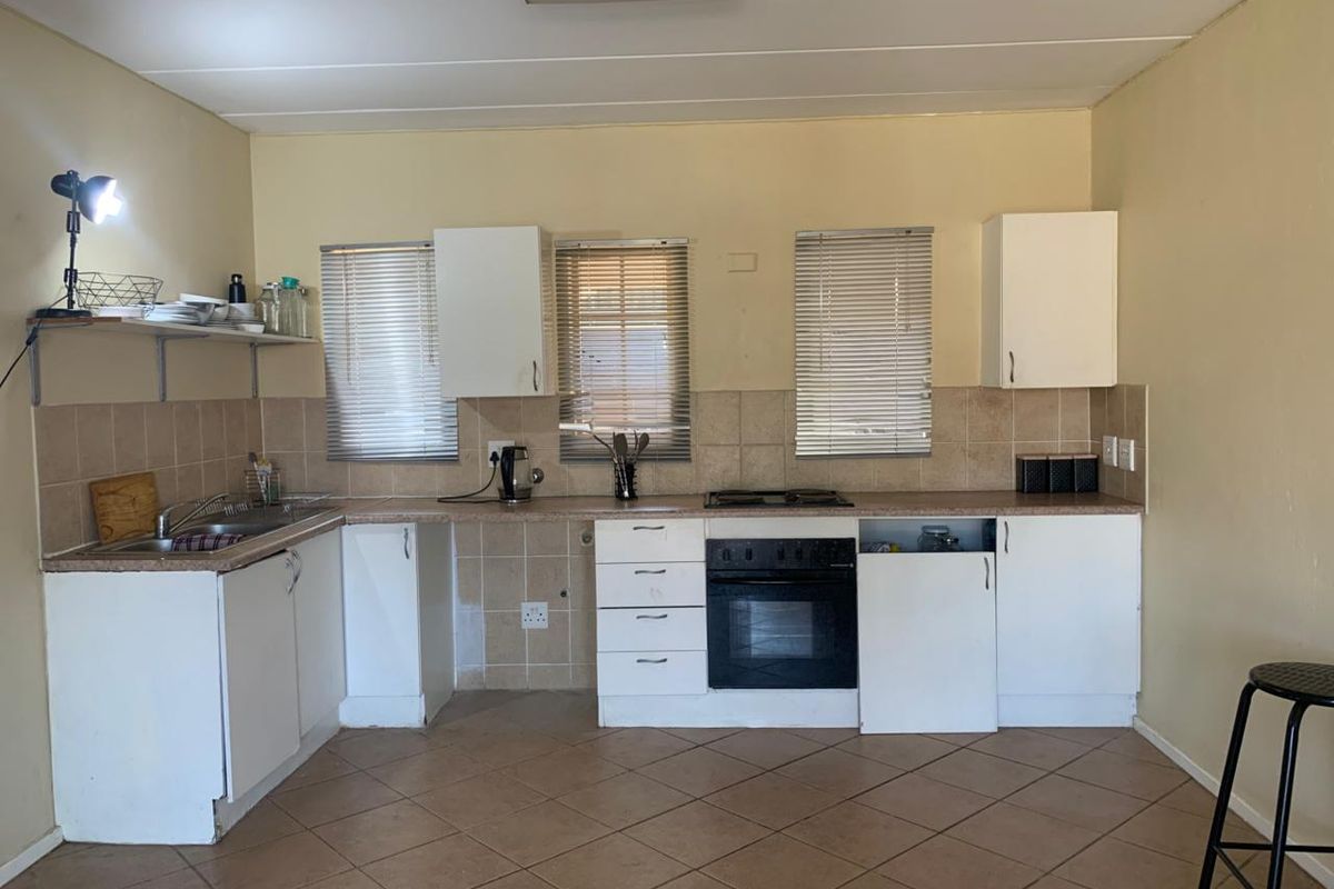 A functional kitchen featuring built-in cabinetry, a tiled backsplash, a built-in oven with hob, and tiled flooring, offering potential for cosmetic updates.
