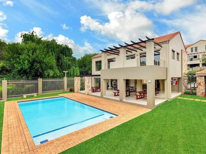A well-maintained outdoor area featuring a swimming pool, brick-paved surround, and a spacious covered patio with a pergola structure.
