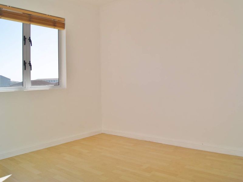 A bright, empty bedroom featuring light-toned laminate flooring and a clean, neutral finish, ready for personalization.