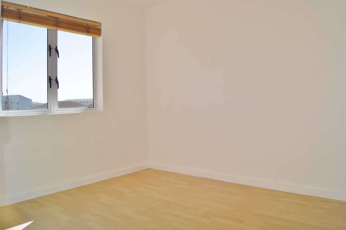 A bright, empty bedroom featuring light-toned laminate flooring and a clean, neutral finish, ready for personalization.