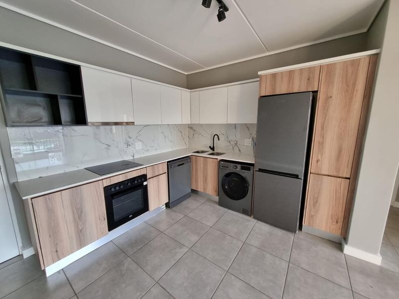 Modern kitchen featuring wood-tone and white cabinetry, marble-look splashback, integrated oven, electric cooktop, and tiled flooring in a clean, contemporary layout.