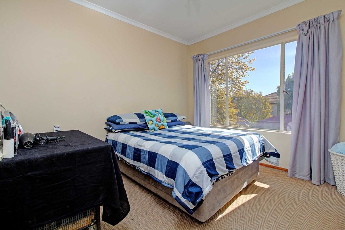 A bedroom featuring neutral wall tones, carpeted flooring, and a large window that allows for natural light and exterior views.