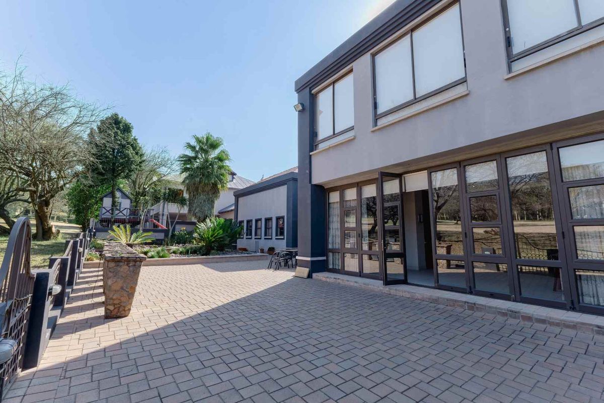 Spacious rear paved patio area featuring large glass sliding doors providing seamless indoor-outdoor flow, overlooking a well-maintained landscaped garden.