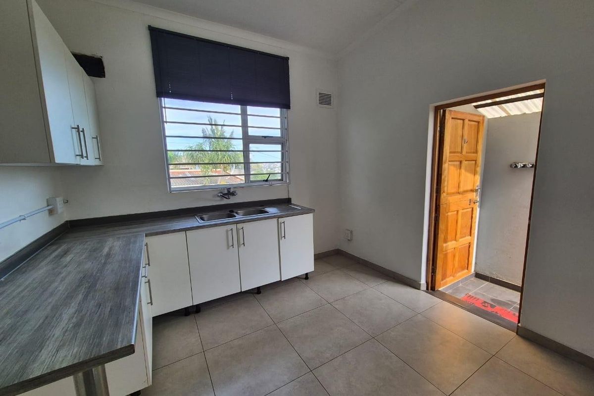 A functional kitchen featuring laminate countertops, built-in cabinetry, and a stainless steel sink, with direct access to an outdoor area.
