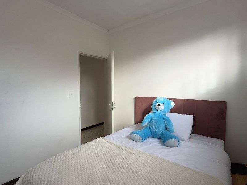 A simple bedroom featuring neutral walls and a doorway leading to an adjacent space.