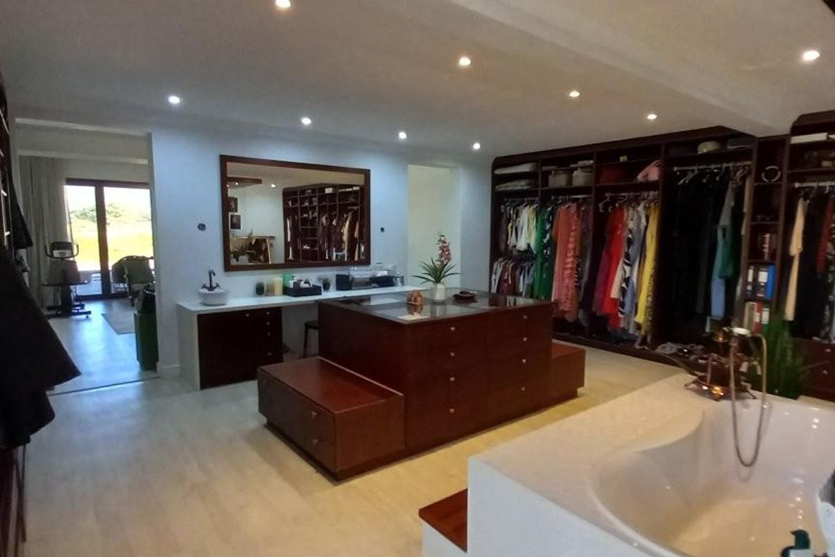 Spacious primary bedroom suite featuring extensive built-in wardrobe cabinetry, a central island dresser, integrated vanity, and a built-in bathtub.