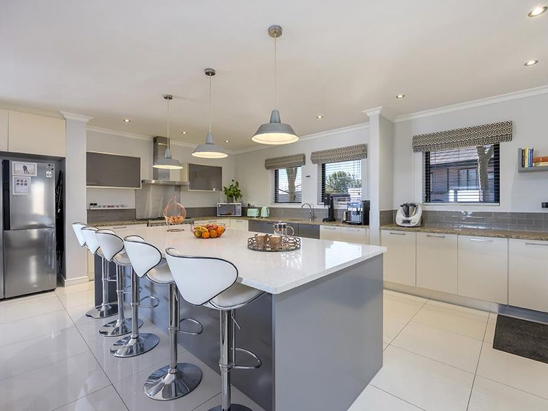 Modern kitchen featuring a large central island with quartz countertops, sleek cabinetry, subway tile backsplash, and high-quality pendant lighting.