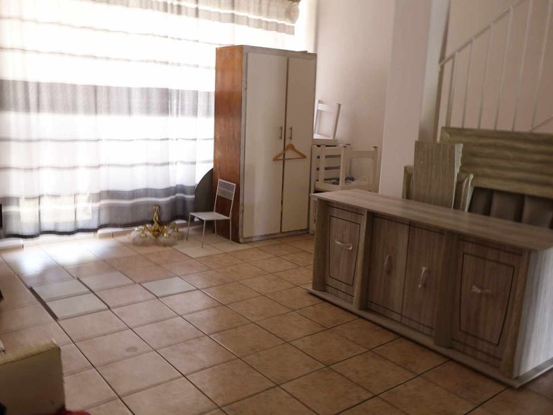 A spacious living area featuring ceramic floor tiles and a staircase, offering a blank canvas for renovation and interior design updates.