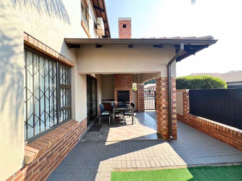 Covered patio area featuring a built-in brick braai, tiled flooring, and brick pillars, providing a functional outdoor entertainment space.