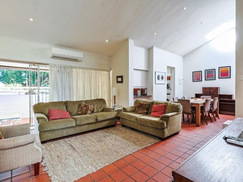 Spacious open-plan living and dining area featuring terracotta tiled flooring, a vaulted ceiling with skylight, and direct access to the outdoor patio.
