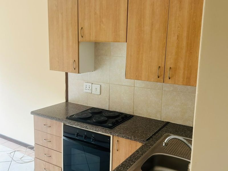 A functional kitchen featuring laminate cabinetry, granite countertops, a built-in oven with electric hob, and a double bowl stainless steel sink.