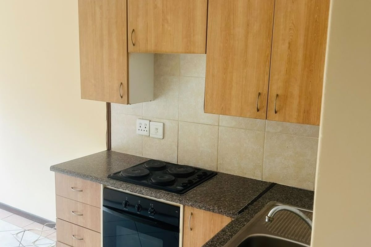 A functional kitchen featuring laminate cabinetry, granite countertops, a built-in oven with electric hob, and a double bowl stainless steel sink.