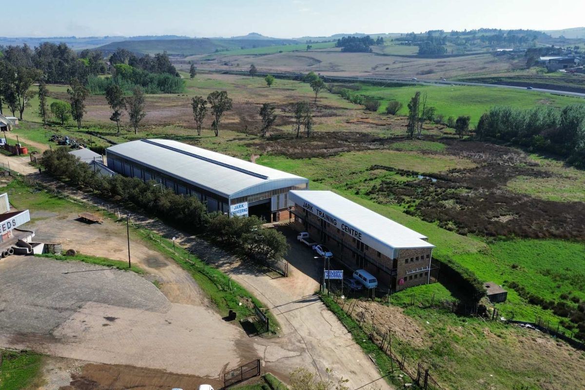 Aerial view of an industrial property featuring warehouse buildings, paved access areas, and surrounding rural landscape.