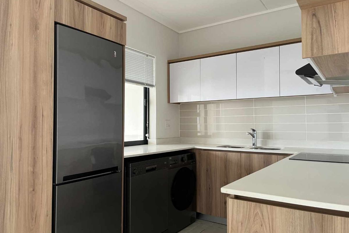 Modern kitchen featuring wood-grain cabinetry, white stone countertops, tiled backsplash, and integrated appliance spaces.