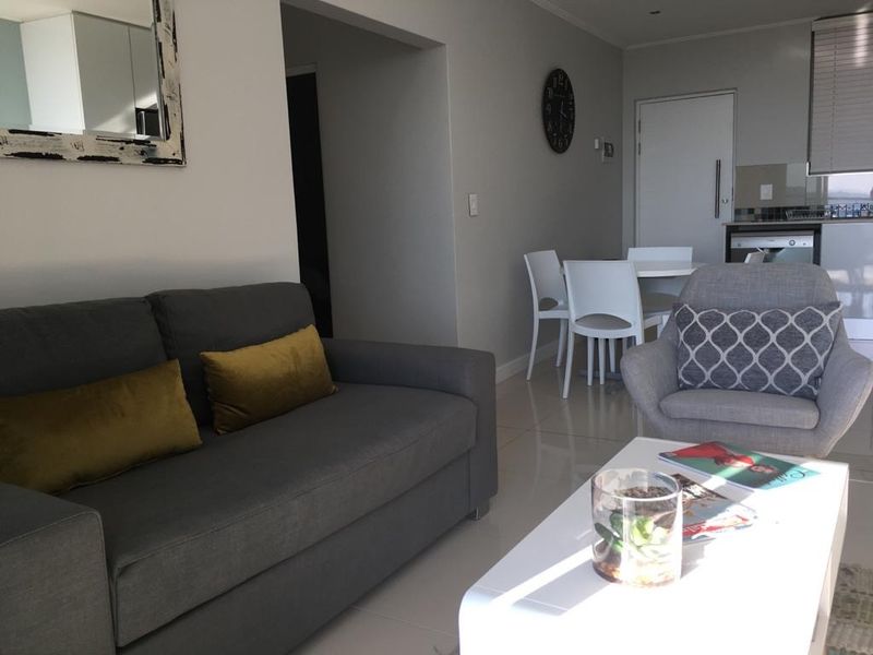 An open-plan living and dining area featuring tiled flooring and a modern kitchen layout with integrated cabinetry and neutral finishes.