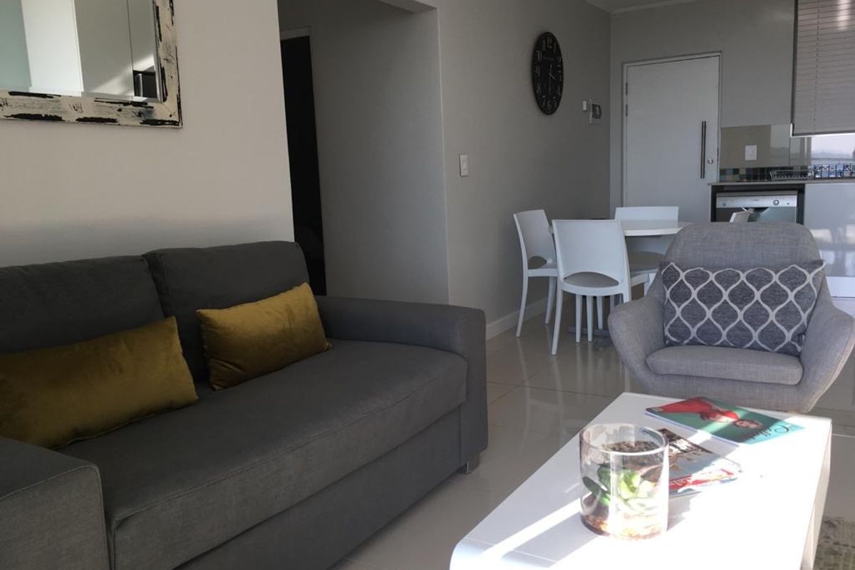 An open-plan living and dining area featuring tiled flooring and a modern kitchen layout with integrated cabinetry and neutral finishes.