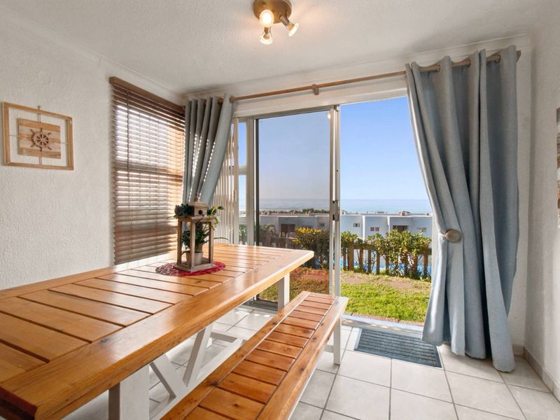Bright dining area featuring ceramic tile flooring and large sliding glass doors that open to a scenic outdoor view.