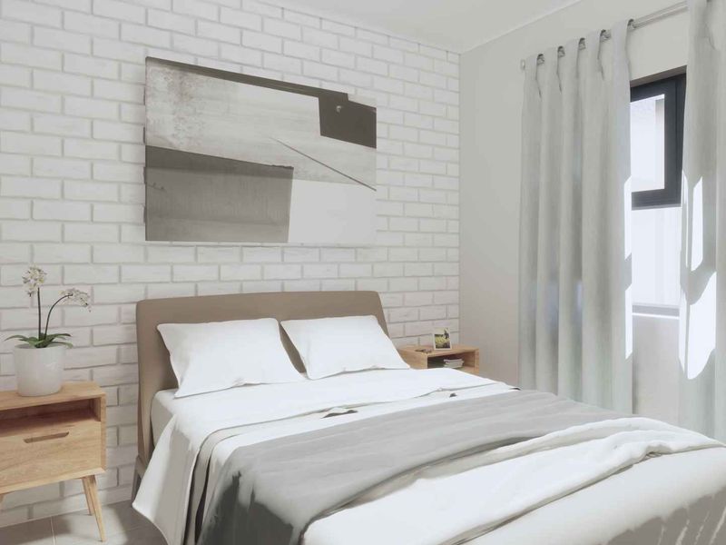 A bright and modern bedroom featuring a white exposed brick accent wall and large window with natural light.