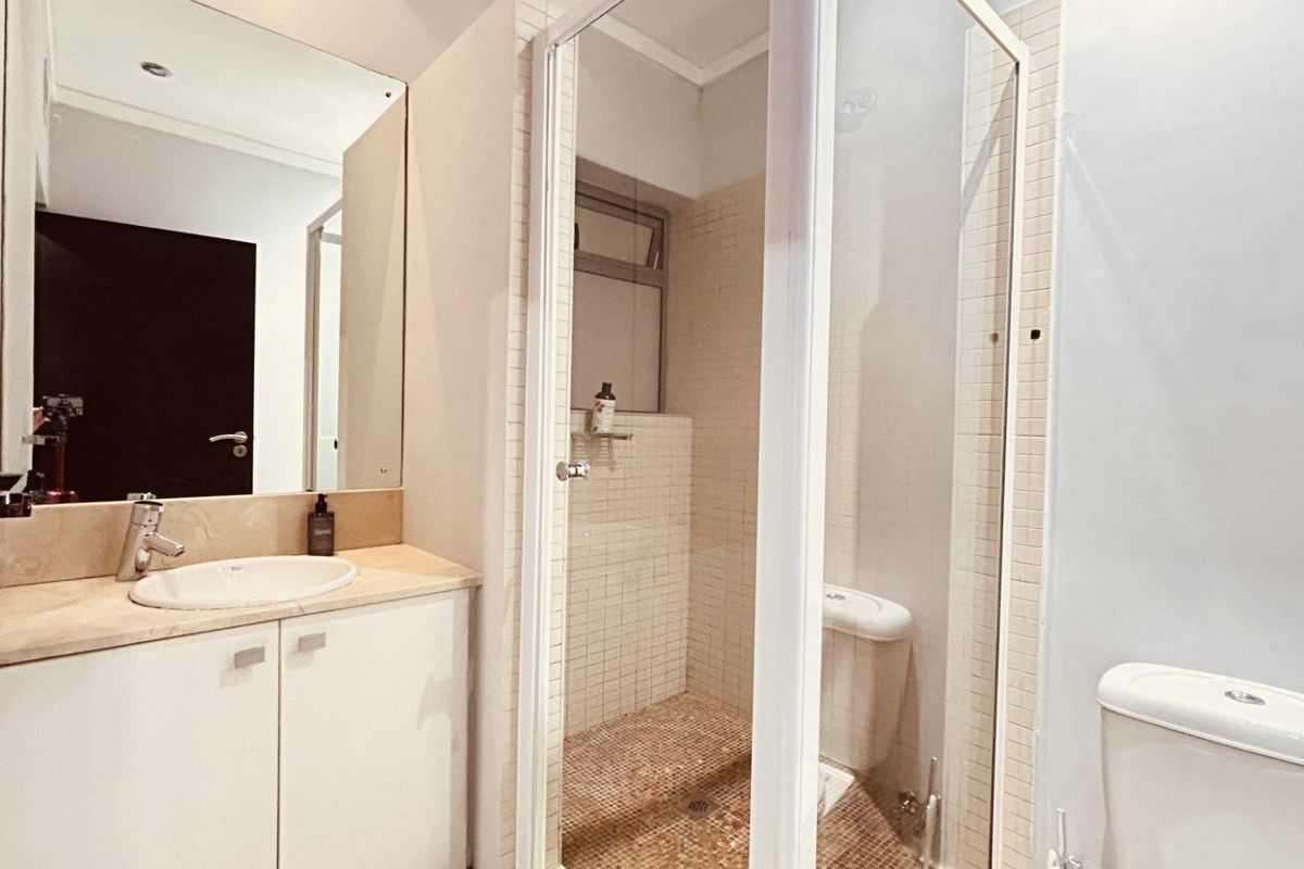 A clean, functional bathroom featuring a vanity with stone countertop, a separate shower enclosure with mosaic tiling, and a standard toilet.