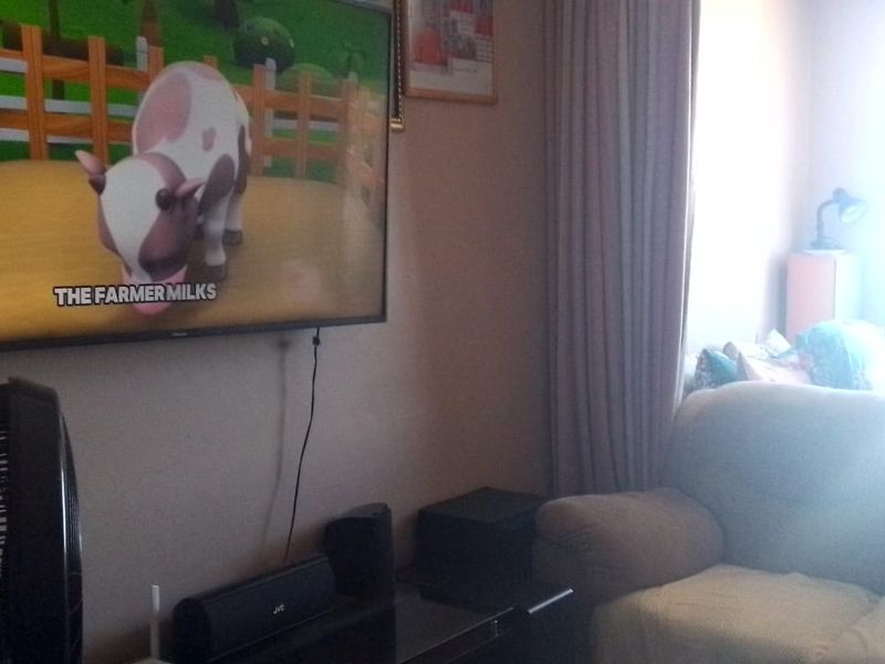 A living room area featuring window curtains and wall-mounted television space.
