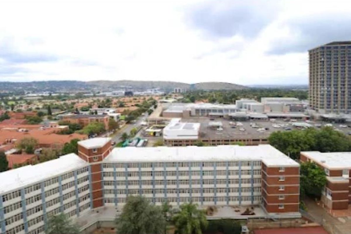 An elevated aerial view of the apartment complex and surrounding urban landscape, showcasing the building's exterior structure and neighborhood context.