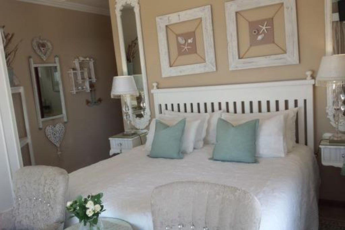 A cozy bedroom featuring a white slatted headboard and neutral wall tones, creating a comfortable and inviting sleeping space.