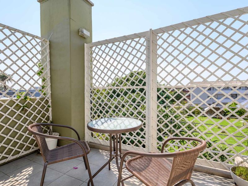 A private balcony featuring tiled flooring and white lattice privacy screens, offering an outdoor space for relaxation.